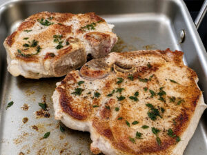 Seared herbed pork chops cooking on griddle