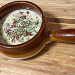 Creamy steakhouse cheeseburger soup in a rustic bowl, topped with crispy bacon, Parmesan, fresh chives, and black pepper.