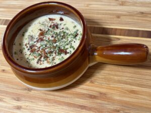 Creamy steakhouse cheeseburger soup in a rustic bowl, topped with crispy bacon, Parmesan, fresh chives, and black pepper.